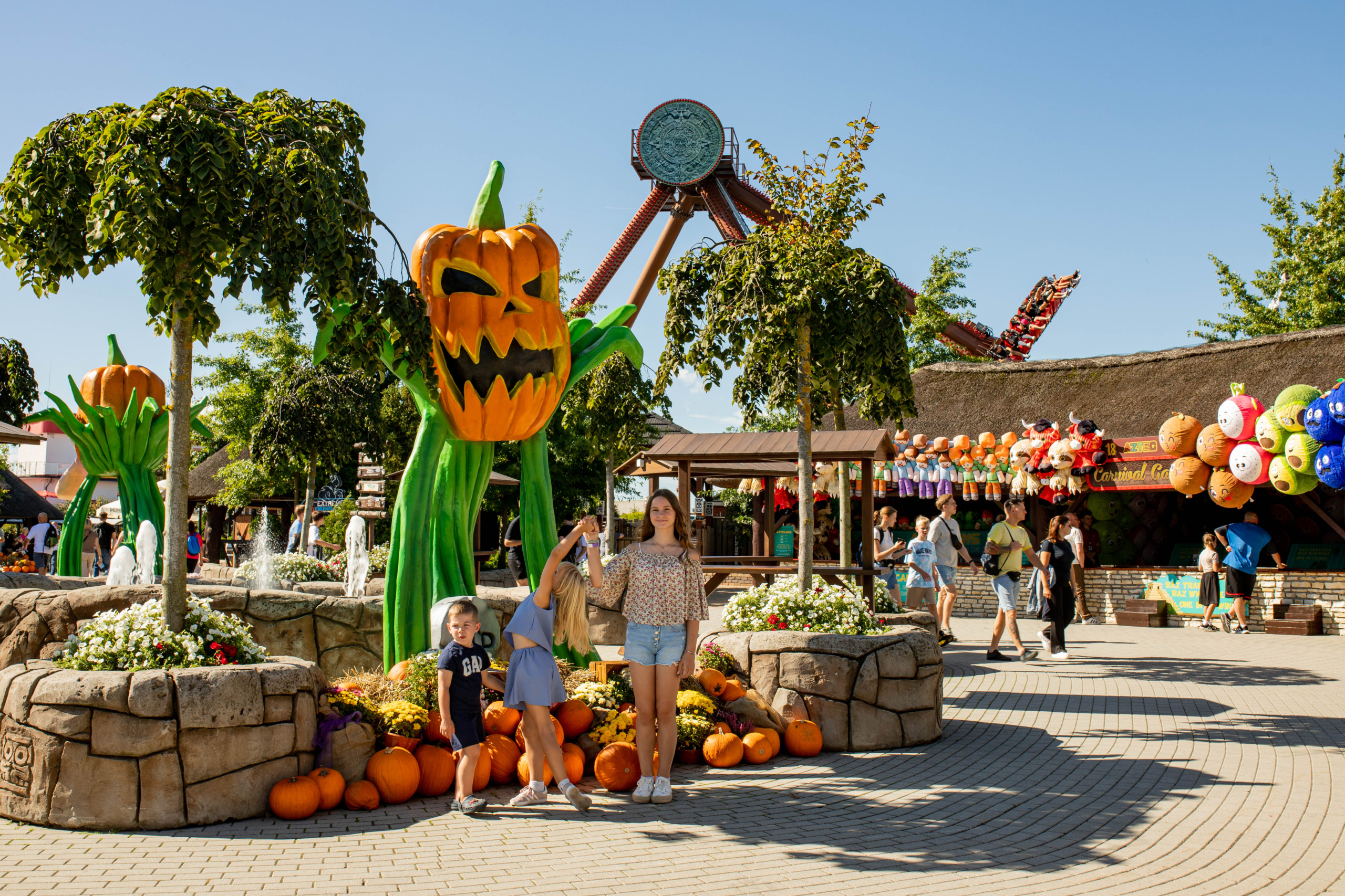 Autumn decorations in the park Halloween-style pumpkin figure and autumn decorations near game stalls at Energylandia on a sunny day.